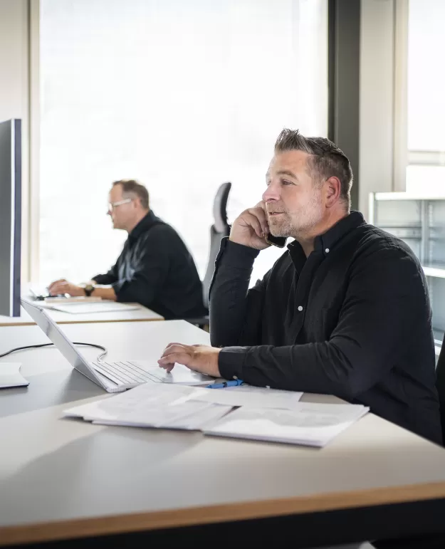 Zwei Mitarbeiter der Vilio AG sitzen an einem Schreibtisch und arbeiten an ihren Computern.